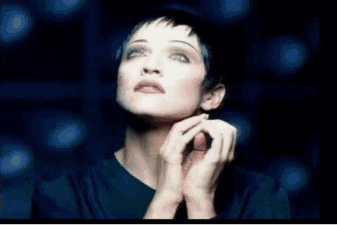 a close up of a woman 's face with her hands folded .