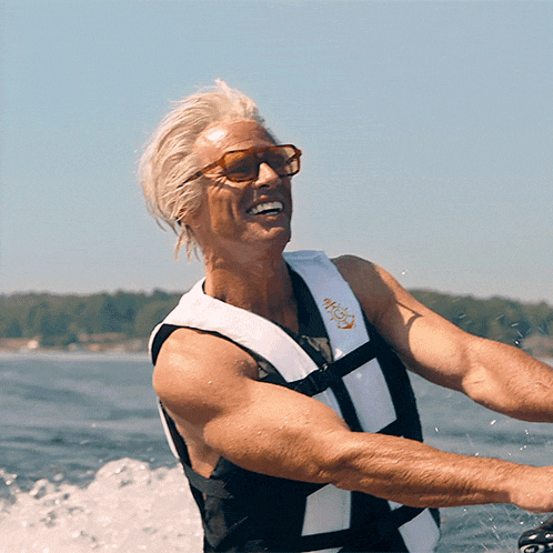 a man wearing sunglasses and a life vest with the word wave on it is riding a wave