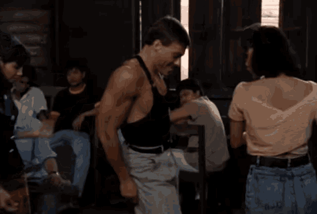 a man in a black tank top is dancing with a woman in a pink top .