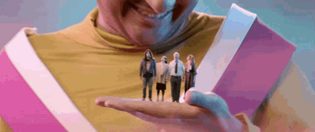 a man in a yellow shirt is holding a small group of people in his hand