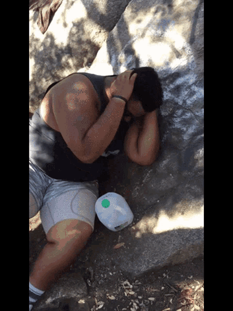 a man laying on the ground with a white container with a green lid on it