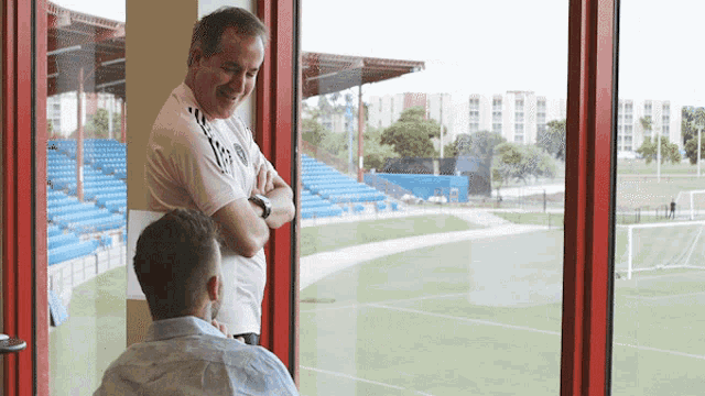 two men are looking out a window at a field