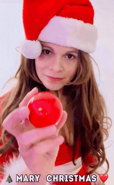 a woman in a santa hat is holding a red ball with the words mary christmas written below her