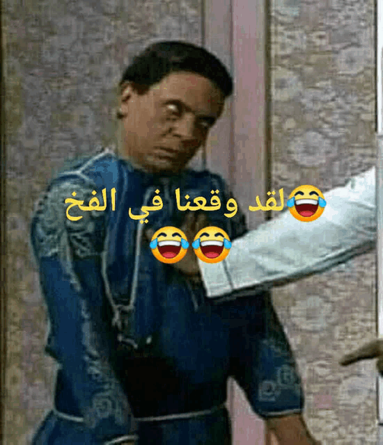 a man in a blue shirt is laughing with arabic writing on it