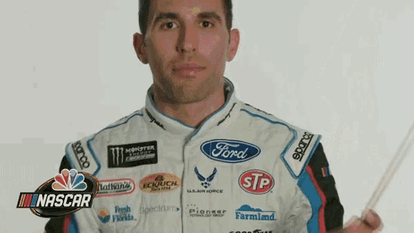a man in a ford racing suit is holding a stick