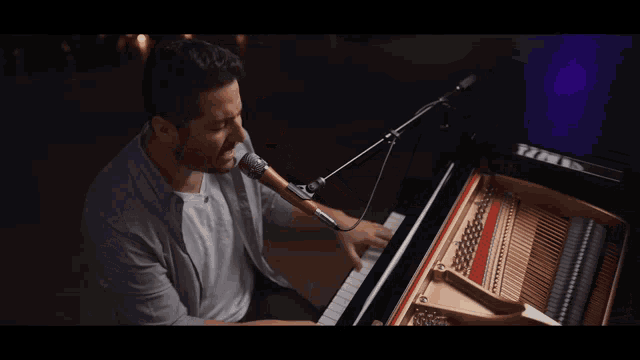 a man singing into a microphone while playing the piano