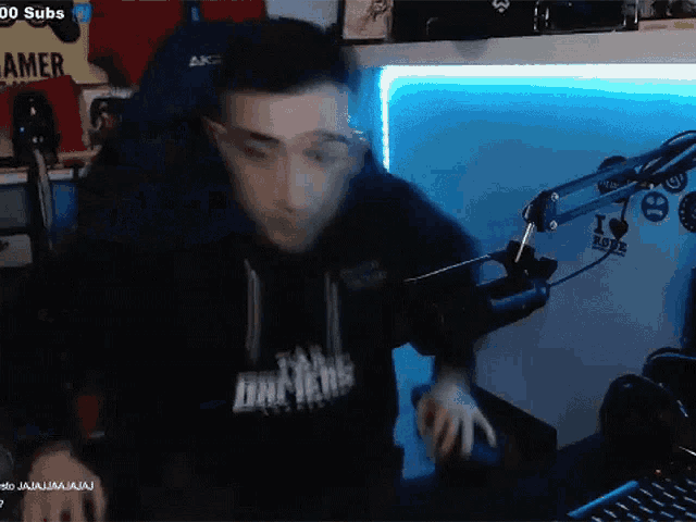 a man wearing a hoodie that says drivers is playing a game on a computer
