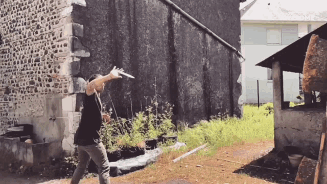 a man is throwing a frisbee in front of a stone building