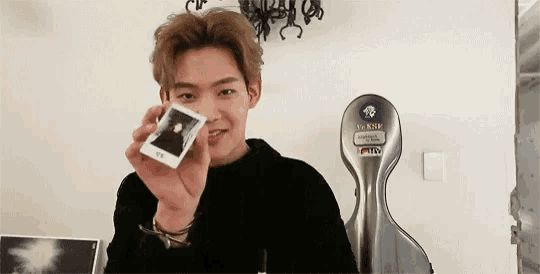 a young man is holding a polaroid picture of himself .