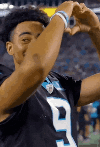 a football player is making a heart shape with his hands during a game .