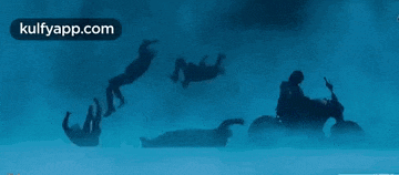 a silhouette of a man riding a motorcycle is falling into the water .