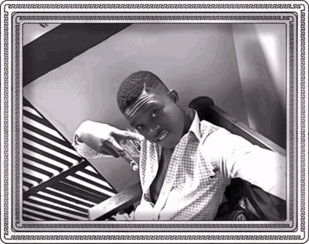 a black and white photo of a man sitting on a staircase taking a selfie .