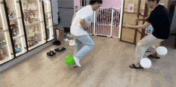 two men are playing with balloons in a room with a sign that says ' a ' on the wall
