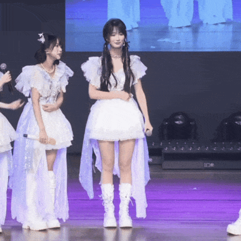 a woman in a white dress stands next to another woman