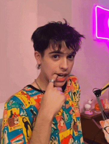 a young man with a ring on his finger is wearing a colorful shirt with cartoon characters on it .