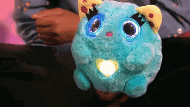 a person is holding a blue stuffed animal with a light inside
