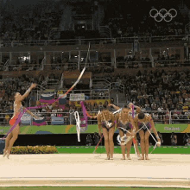 a group of gymnasts are performing in front of a crowd at the rio 2016 olympic games