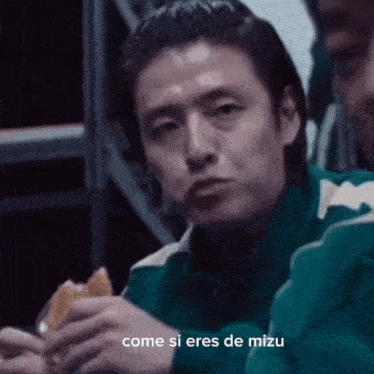 a man eating a sandwich with the words come si eres de mizu written below him