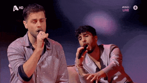 a couple of men singing on a stage with a hd logo in the background