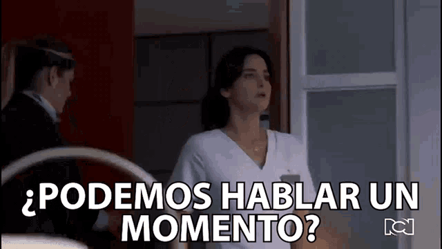 a woman in a white scrub top is standing next to a man in a suit and says " podemos hablar un momento "