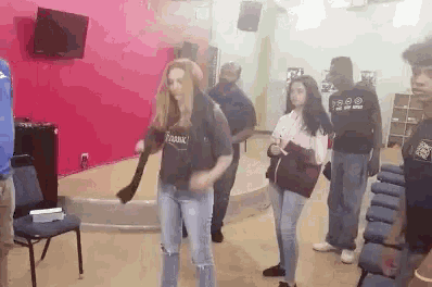 a group of people are dancing in a room with a red wall behind them .