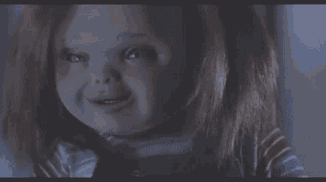 a close up of a doll making a funny face in a dark room .