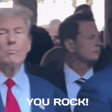 a man in a suit and tie is standing next to another man who says you rock