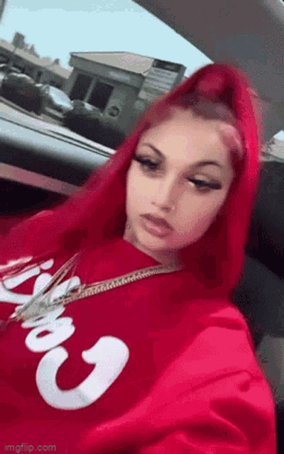 a woman with red hair is wearing a red sweatshirt with the word supreme on it .