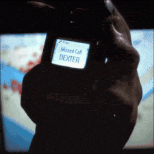 a person holding a cell phone that says missed call dexter on it