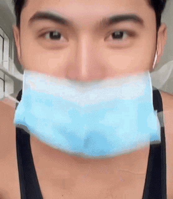 a man wearing a blue face mask with a black tank top .