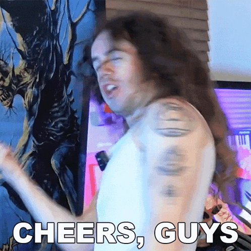 a man with long hair says cheers guys while dancing