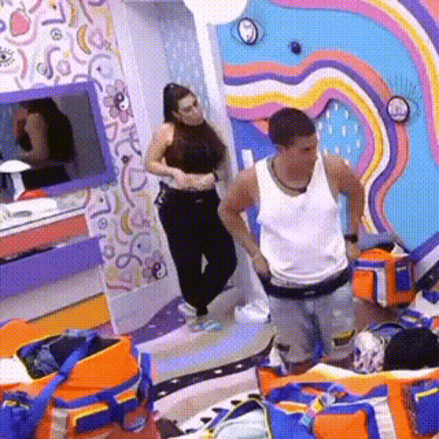 a man and a woman are standing next to each other in a room with a colorful wall .