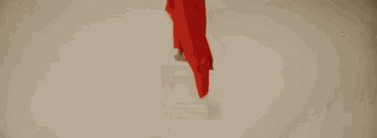 a woman in a red dress is standing in front of a white wall