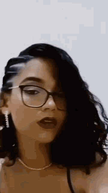 a close up of a woman wearing glasses and a pearl necklace .