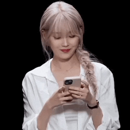 a woman with blonde hair is holding a cell phone in her hands .