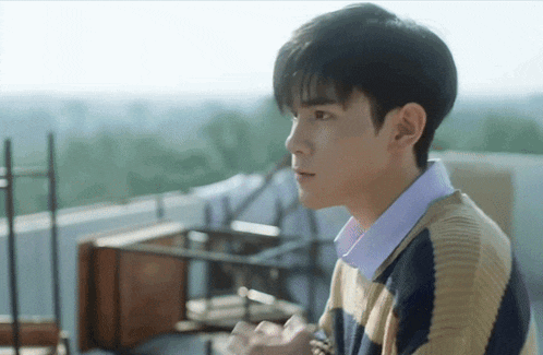 a young man wearing a striped sweater and a blue shirt