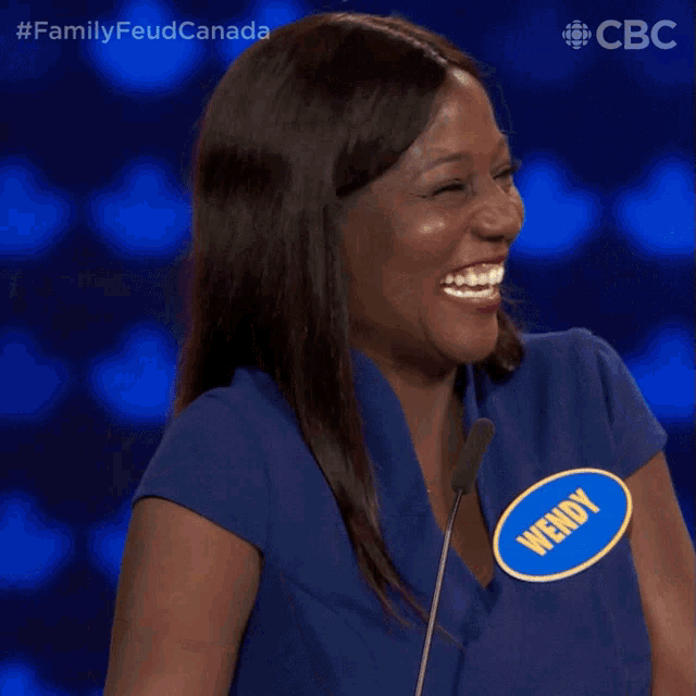 a woman with a name tag that says wendy laughs in front of a microphone