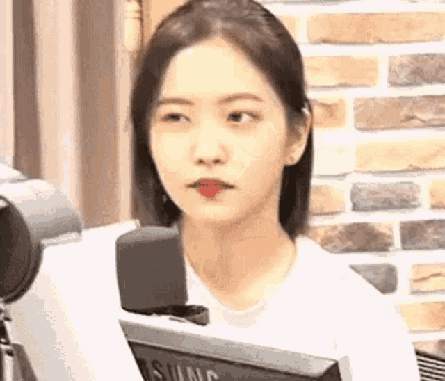 a young woman is sitting in front of a computer monitor and looking at the camera .