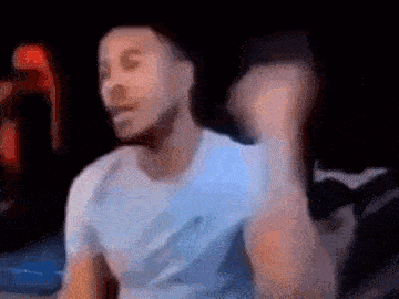 a man in a white shirt is dancing in a dark room with a blurry background .
