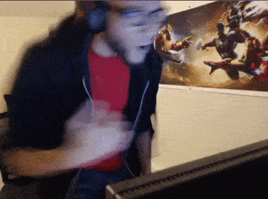 a man wearing headphones and a red shirt is sitting in front of a computer screen