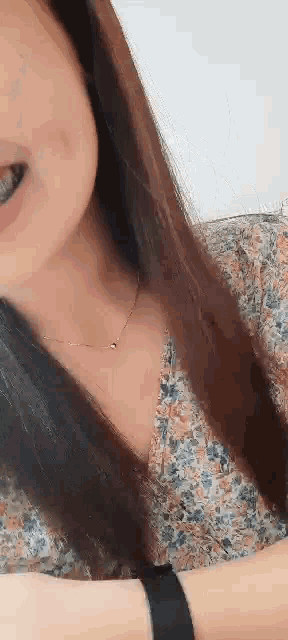 a close up of a woman 's face with long hair wearing a necklace .