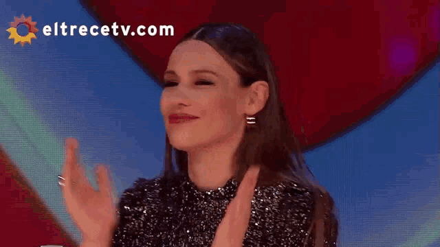 a woman is clapping in front of a eltrecetv.com logo