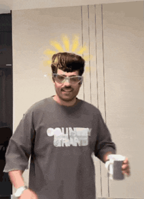 a man wearing glasses and a shirt that says country grand is holding a cup of coffee .