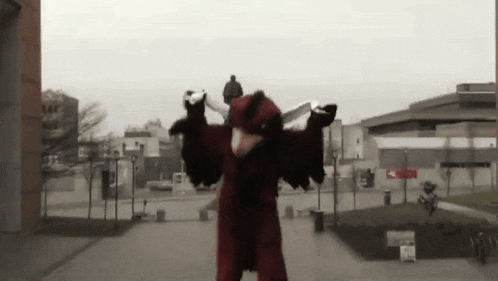 a person in a red and black costume is standing in front of a building