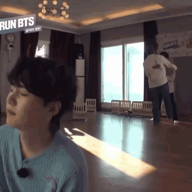 a man is standing in a room with a sign that says run bts on it .