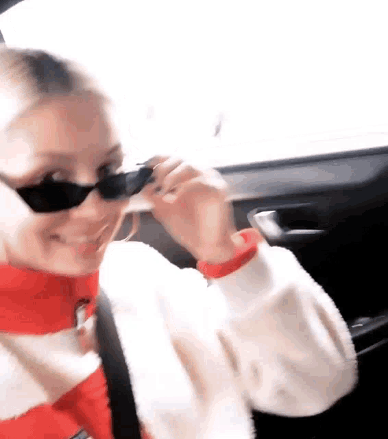 a woman wearing sunglasses is sitting in a car and smiling