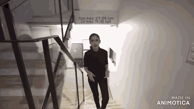 a woman is walking down a set of stairs with a sign that says floor area 319-398 sqm lot area 70-100 sqm
