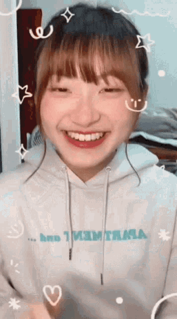 a girl wearing a white hoodie that says ' i 'm thirsty ' on it smiles