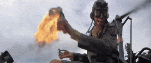 a man wearing a helmet and goggles is holding a flamethrower .