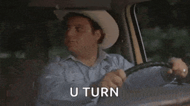 a white suv is driving down a wet road with the words `` u turn '' written on the side of it .